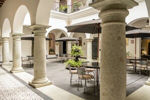 A spacious courtyard with columns, outdoor seating, and potted plants. - Hotel Boutique Naura Centro (Oaxaca)