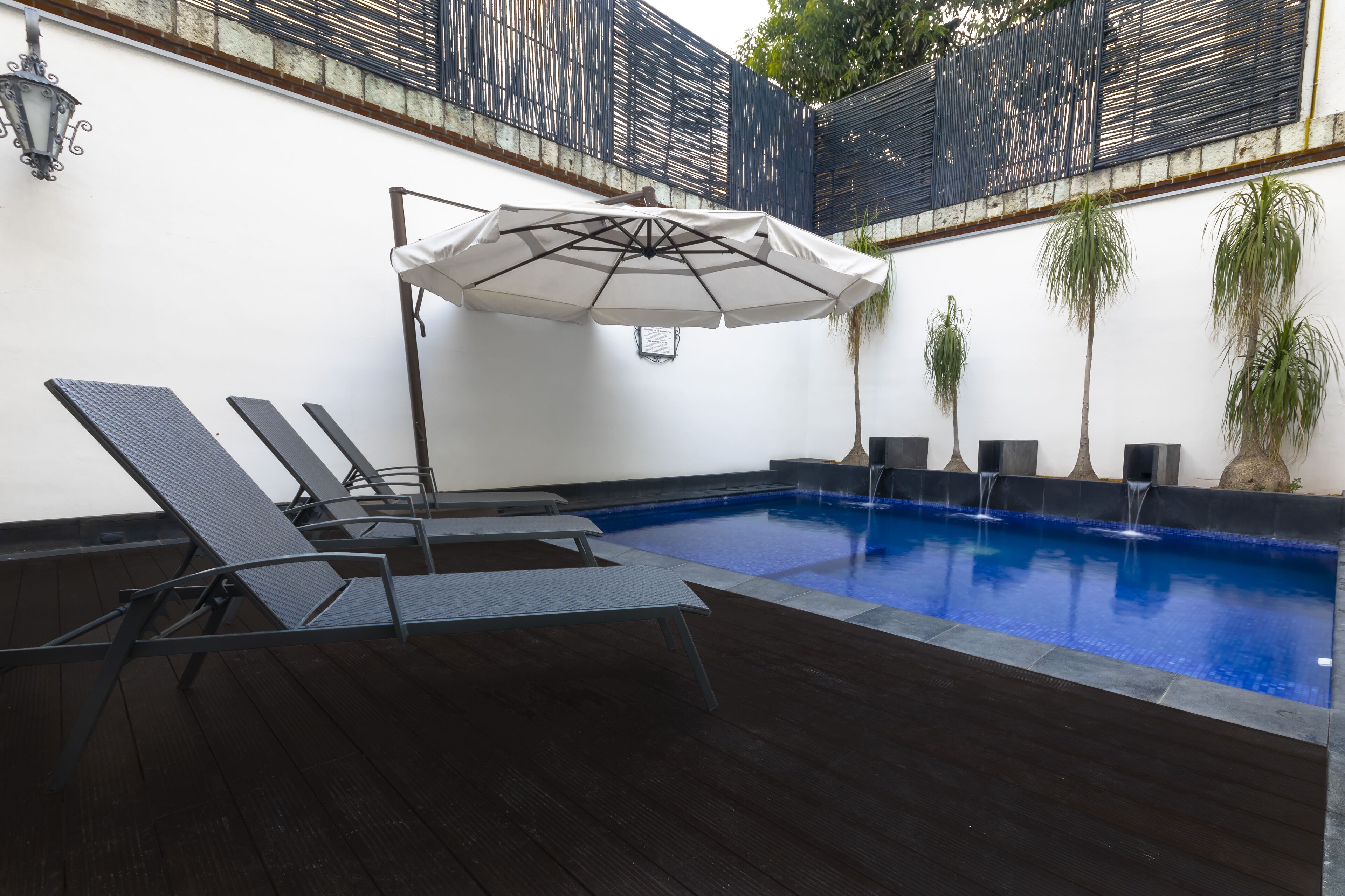 A pool area with lounge chairs and an umbrella.