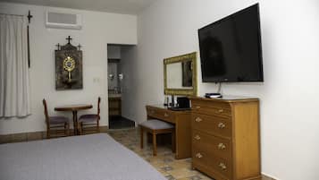 Una habitación de hotel con una cama, un aparador de madera, un escritorio con una silla, un televisor y un espejo.