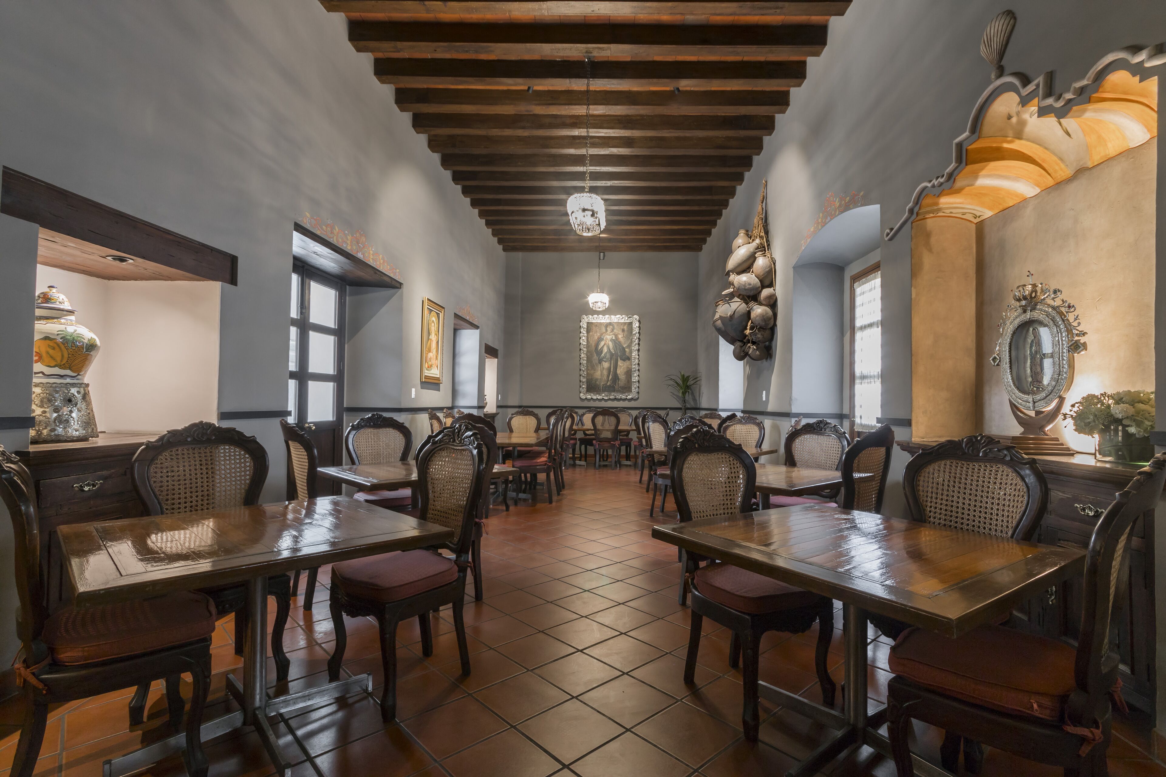 A restaurant with wooden tables and chairs, a tiled floor, and a chandelier.