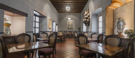 A restaurant with wooden tables and chairs, a tiled floor, and a chandelier.
