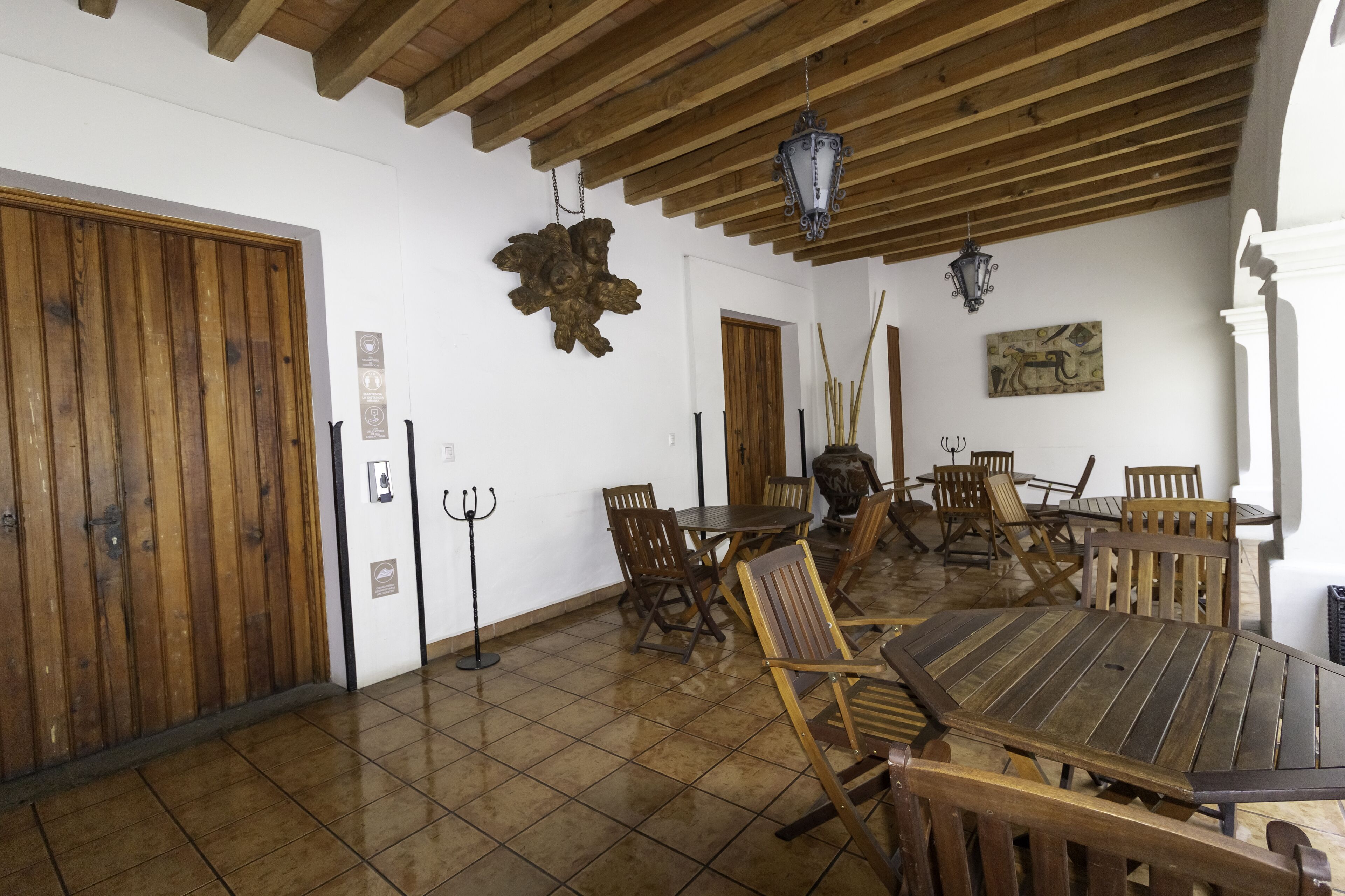 A dining area with wooden tables and chairs, a chandelier, and a rustic decor.