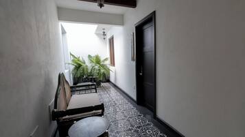 A narrow hallway with a patterned floor, a black door, and a seating area with a table and chairs.