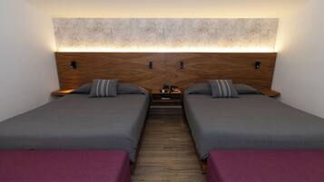 A double room with two beds, a wooden headboard, and a nightstand between them.