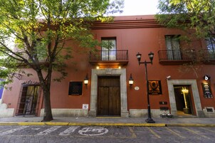 Un edificio rojo con puerta de madera, un balcón y una farola.