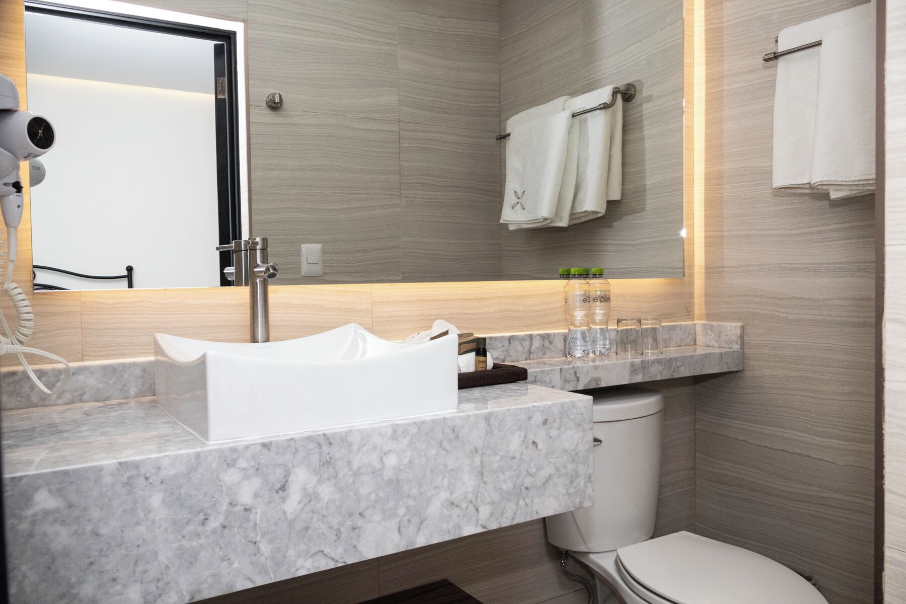 A modern bathroom with a marble sink, a toilet, and a towel rack.