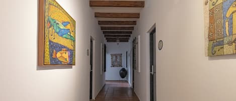 Un pasillo con vigas de madera, suelo de baldosas y obras de arte en las paredes.