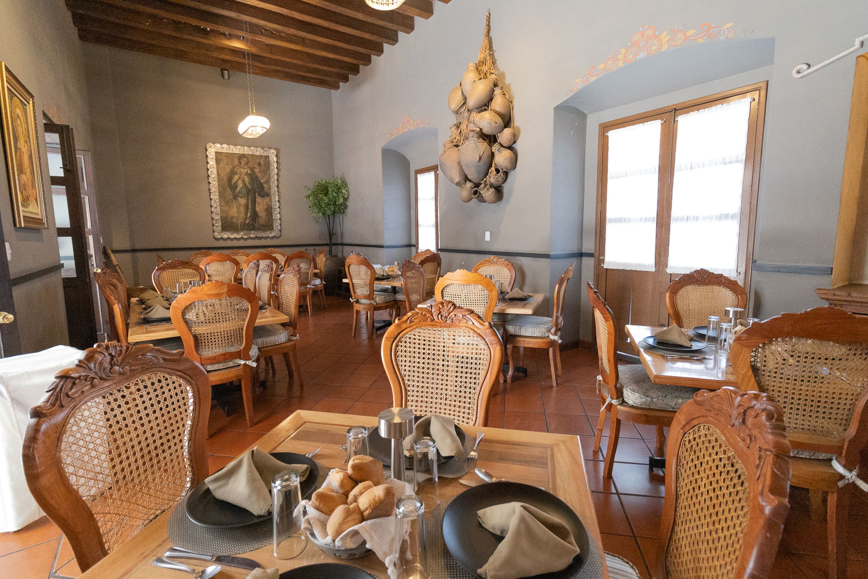A restaurant with wooden furniture, a chandelier, and a painting on the wall.