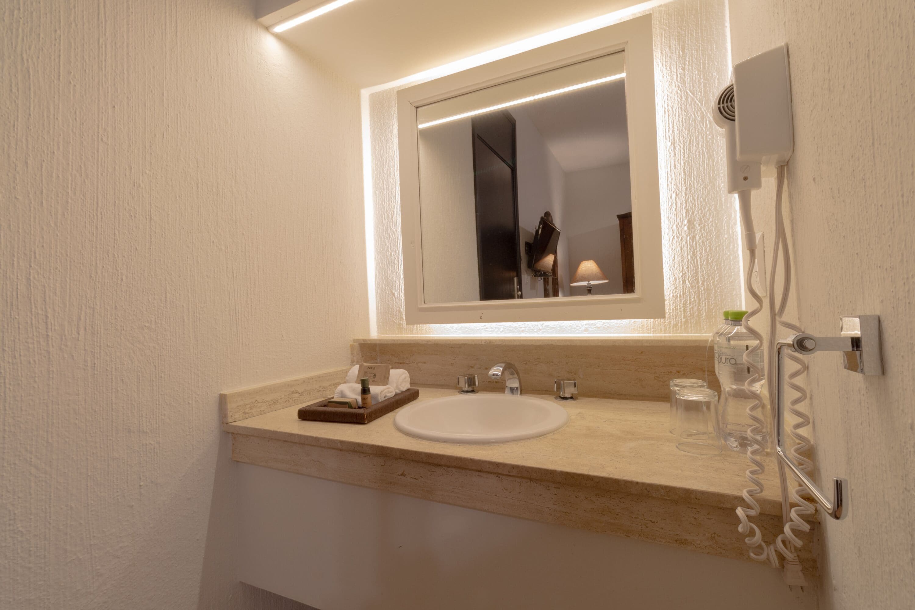 A bathroom with a white sink, a mirror, and a towel rack.