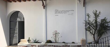 A courtyard with a pool, a stone bench, and a wall with a quote.