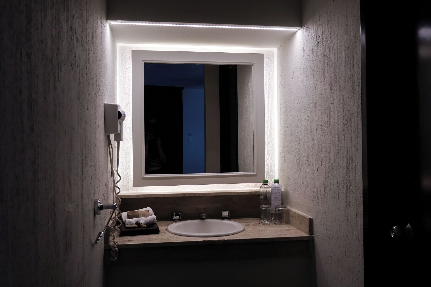 A bathroom with a white sink, a mirror, and a towel rack.