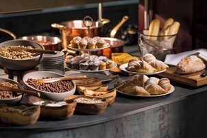 Een buffet met diverse gerechten, waaronder gebak, fruit en granen.