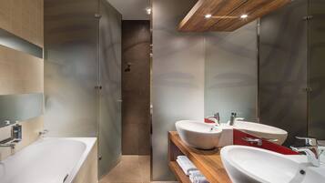 A modern bathroom with a large bathtub, two sinks, and a wooden vanity.