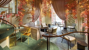 A modern interior with a staircase, seating area, and decorative foliage.