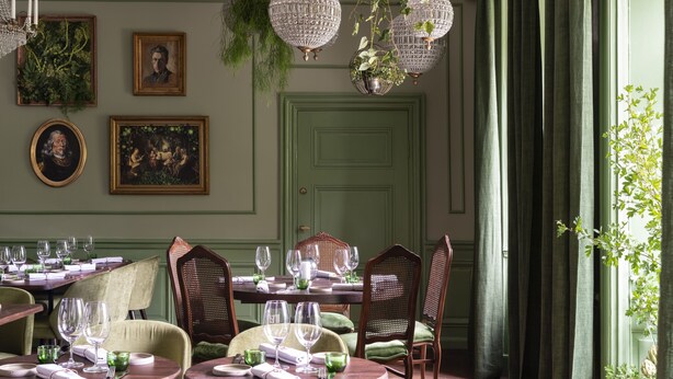 Comedor con puerta verde, retratos enmarcados y candelabros de cristal colgantes.