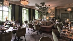 Un comedor con varias mesas dispuestas para una comida, con candelabros elegantes y un ambiente acogedor.