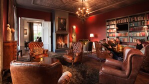 Una biblioteca tradicional con sillones de cuero, chimenea y una amplia estantería.