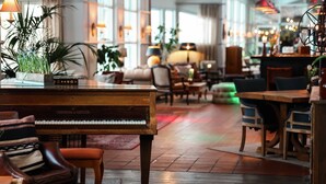 Un gran piano en una sala de estar amplia y luminosa, con asientos cómodos y ventanas grandes.