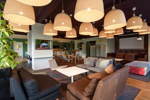 A modern lounge area with multiple seating options, including sofas and chairs, under large woven pendant lights. - The Nooq Alvik (Bromma)