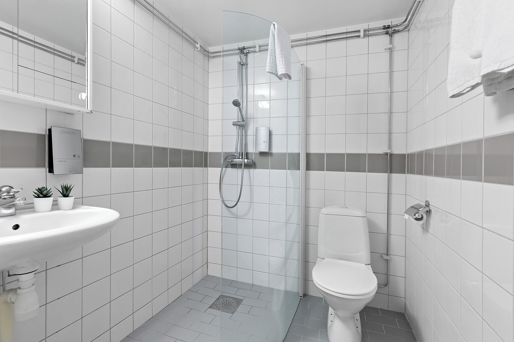 A modern bathroom with a shower, toilet, and sink.