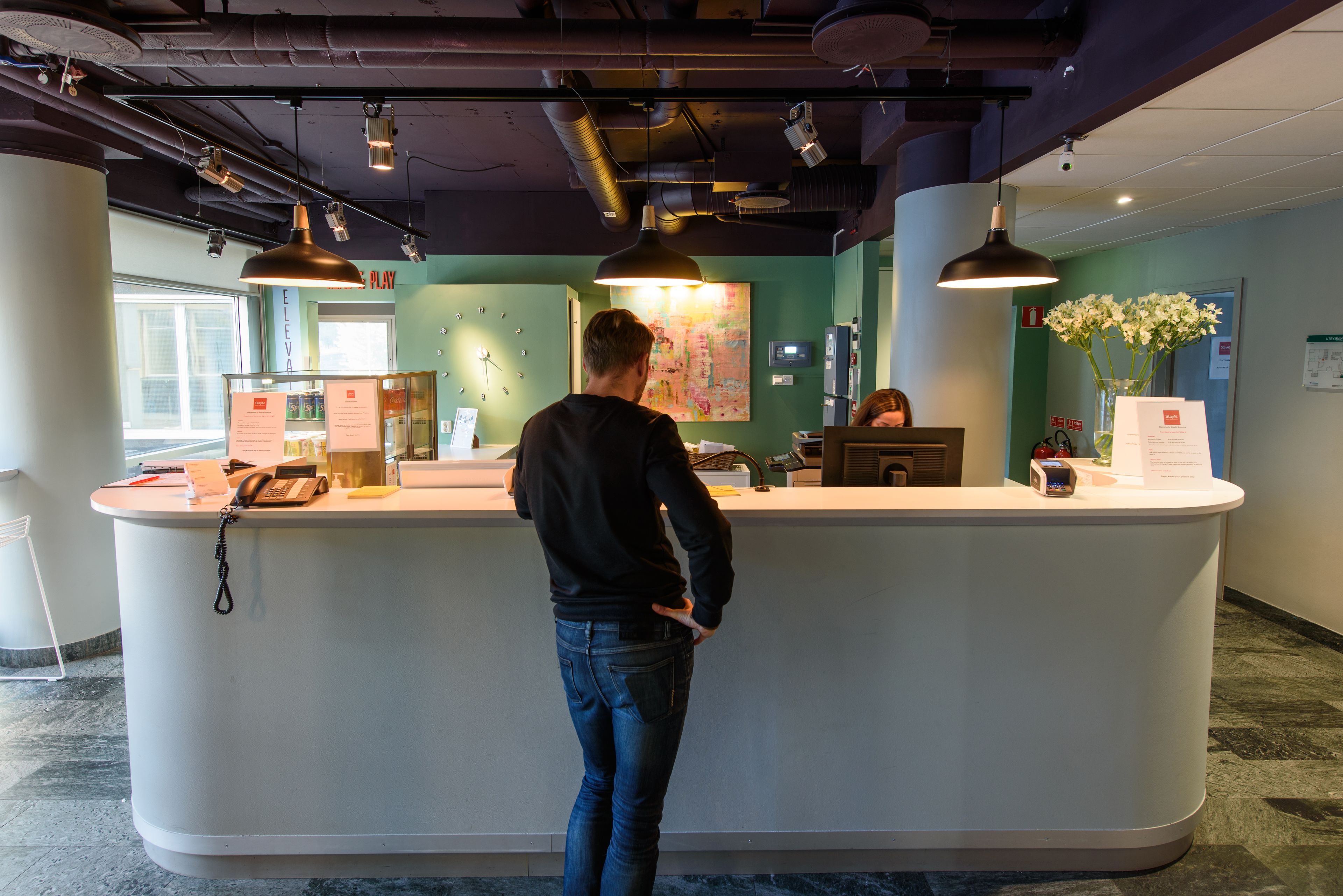 A reception desk with a map, a phone, and a vase with flowers.
