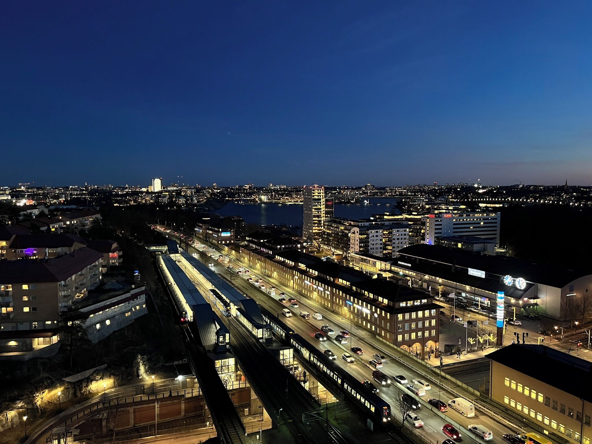 Een nachtelijke stadsgezicht met een opvallende verhoogde spoorlijn en omliggende gebouwen.