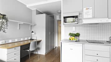 A modern kitchen with white cabinetry, a wooden countertop, and a built-in microwave. There is a small plant on the countertop and a white chair near the kitchen counter.