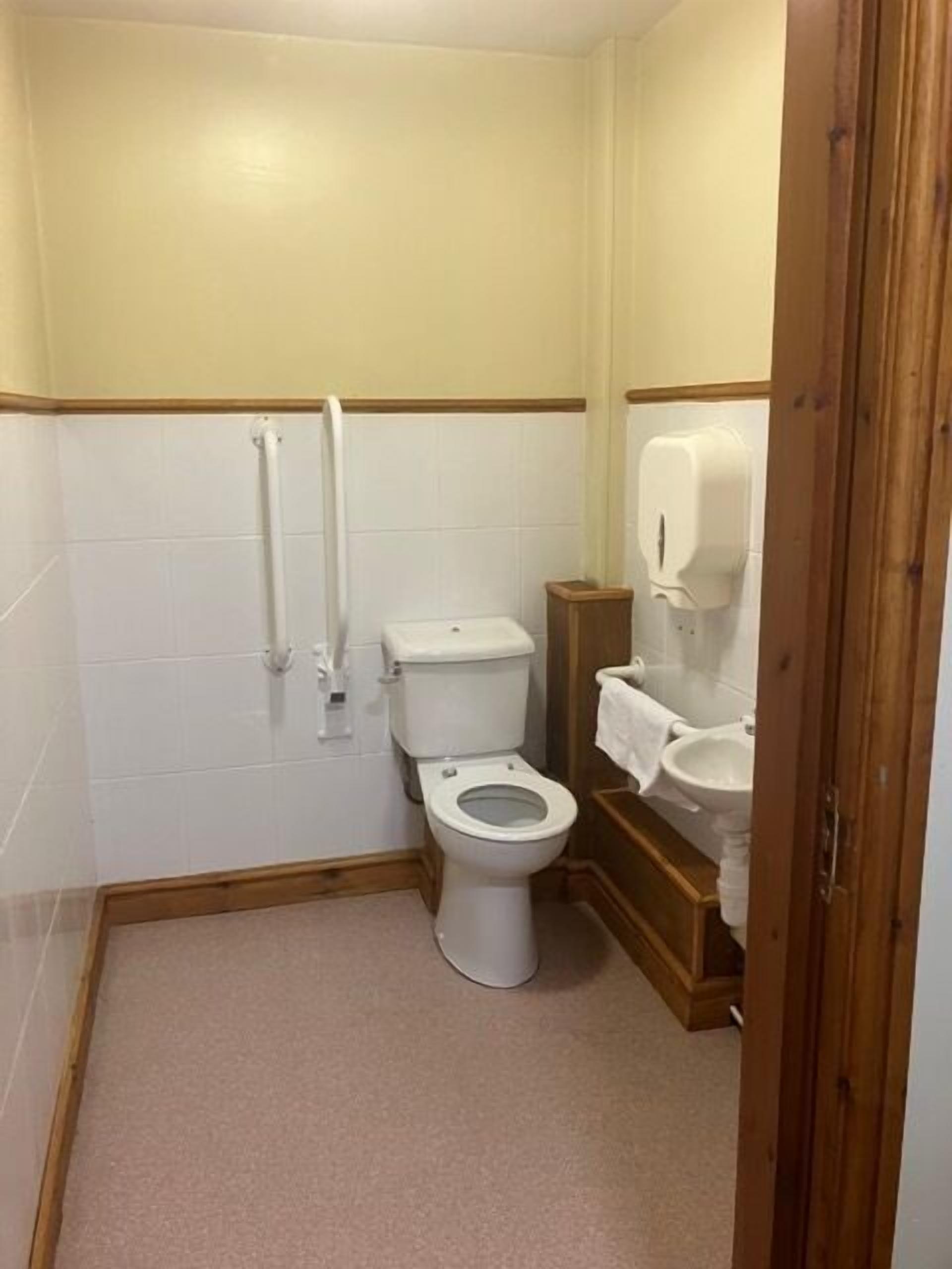 A small, compact bathroom with a toilet, a hand dryer, and a sink.