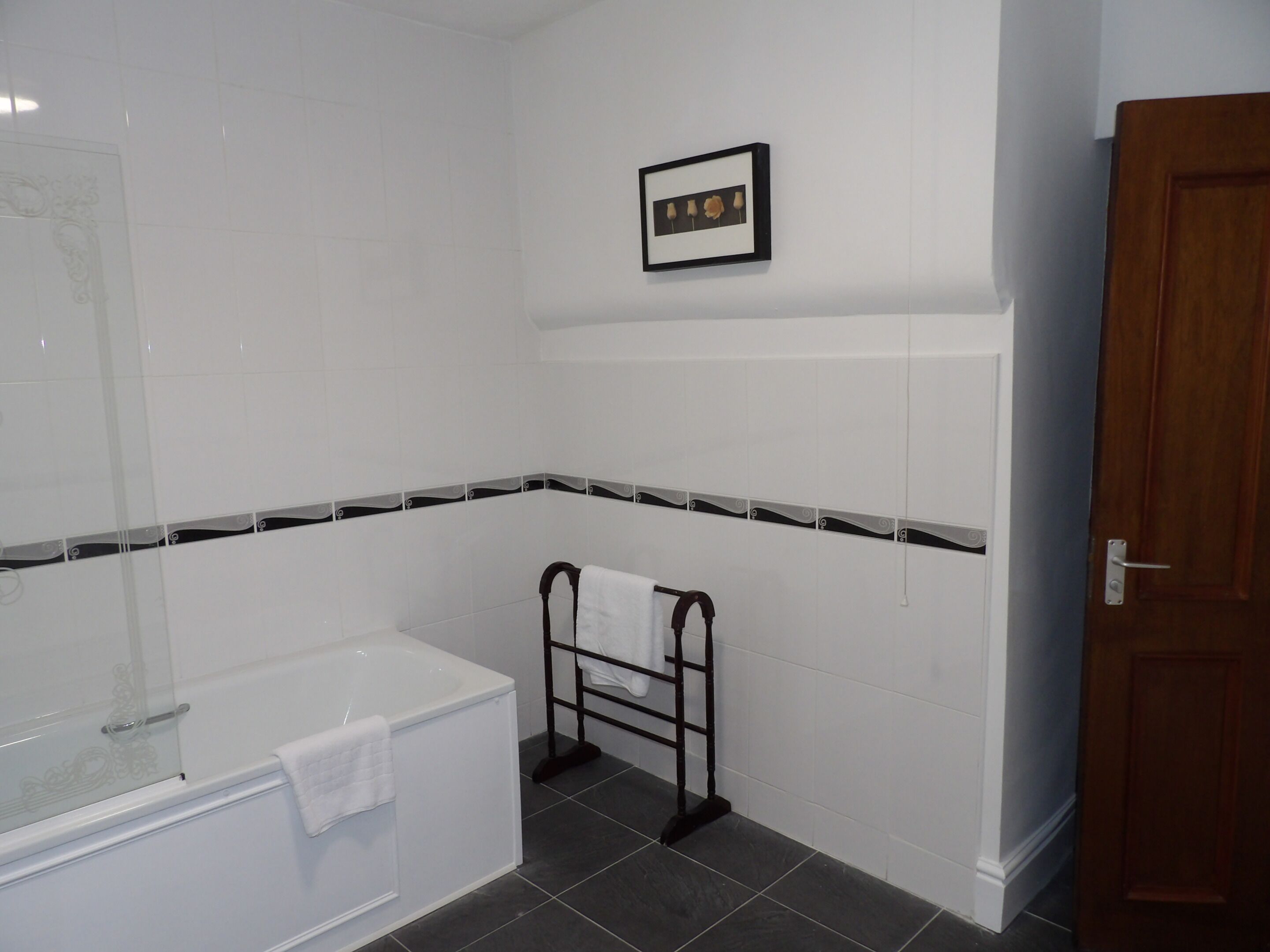 Un bagno con una vasca, un porta asciugamani e un quadro appeso al muro.