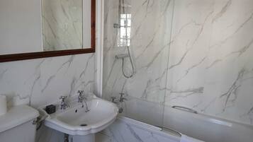 Un baño con lavamanos, inodoro y bañera de mármol.