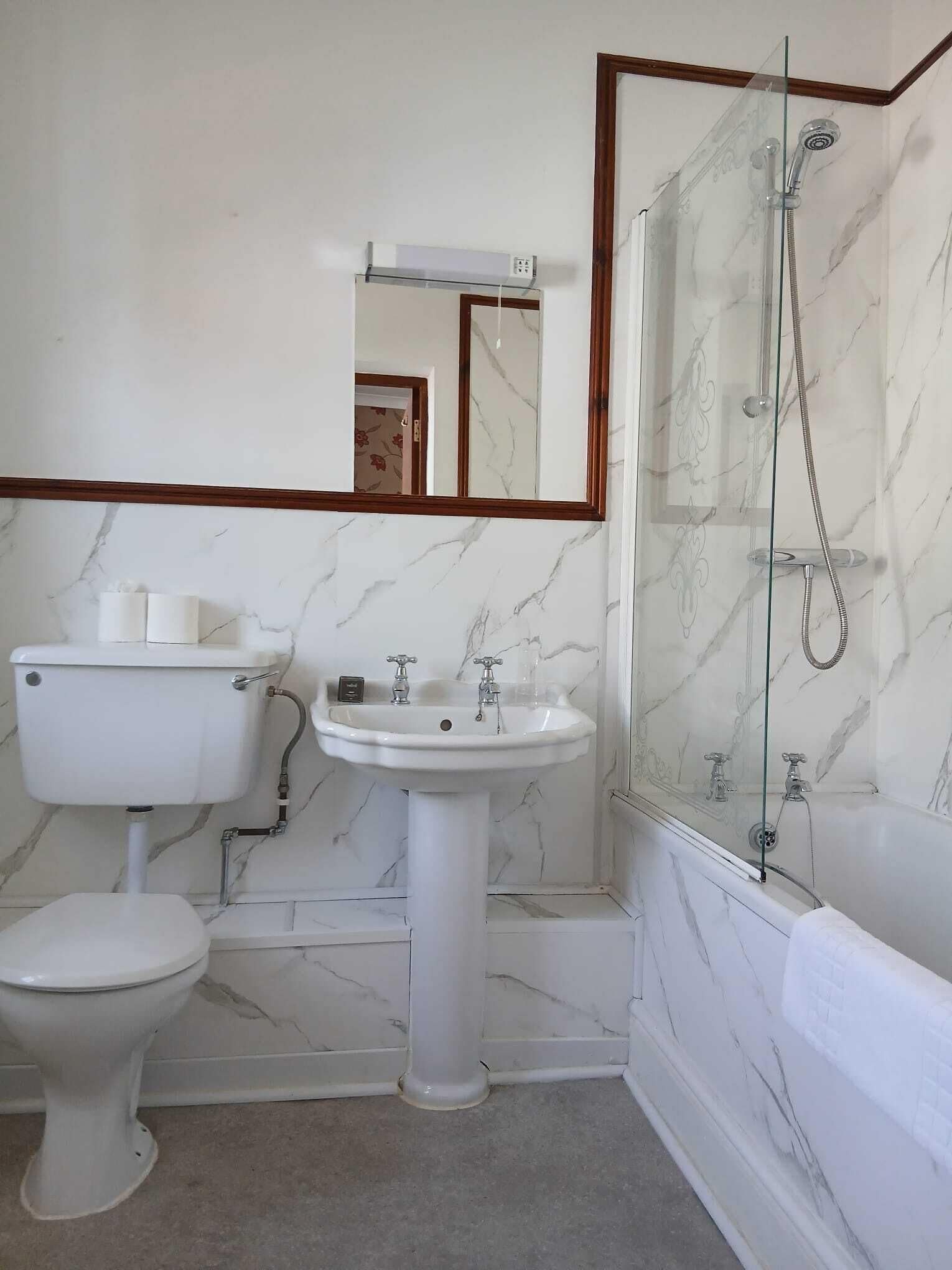 A bathroom with a toilet, sink, and shower.