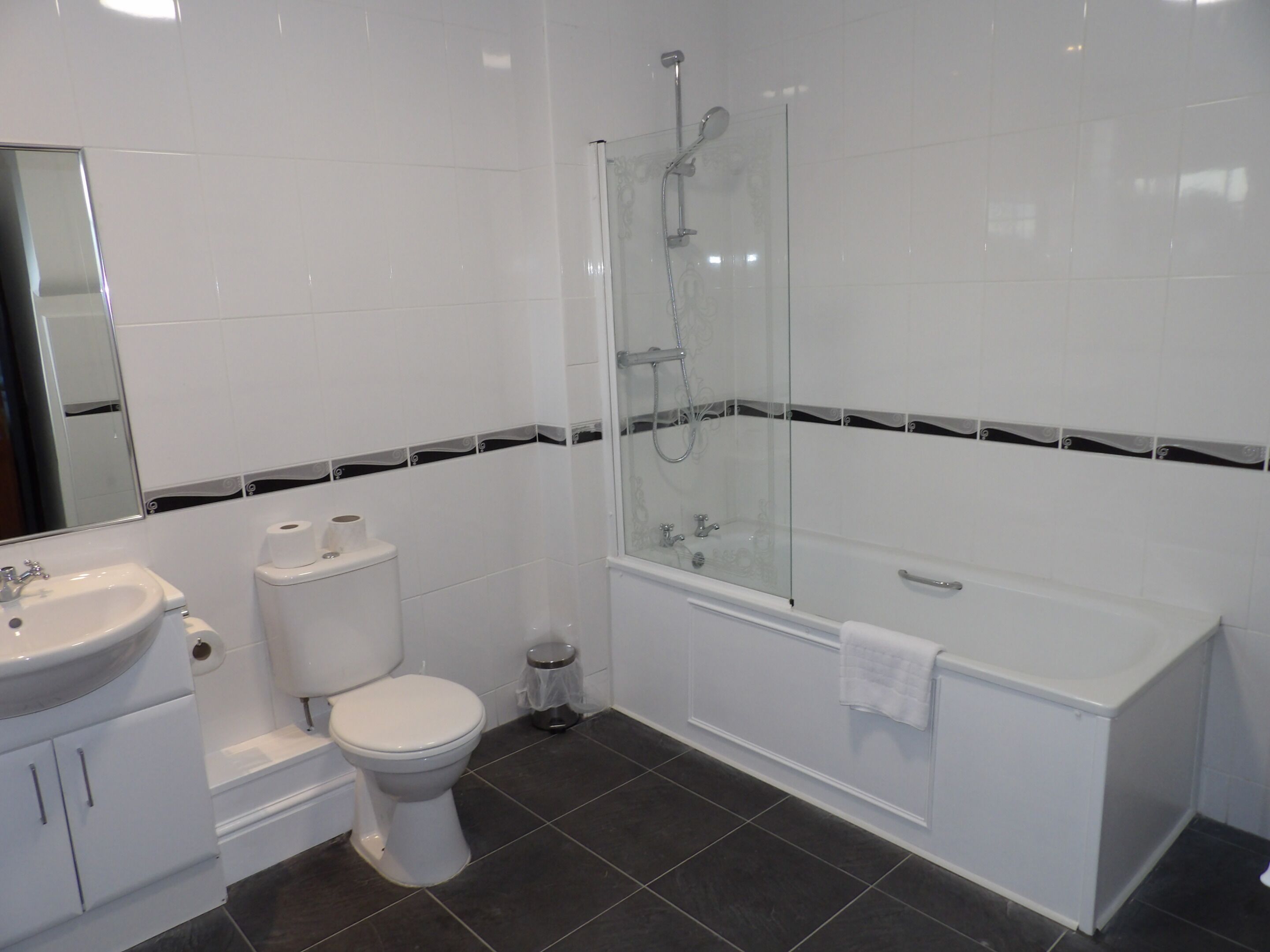 A modern bathroom with a white sink, toilet, and bathtub.