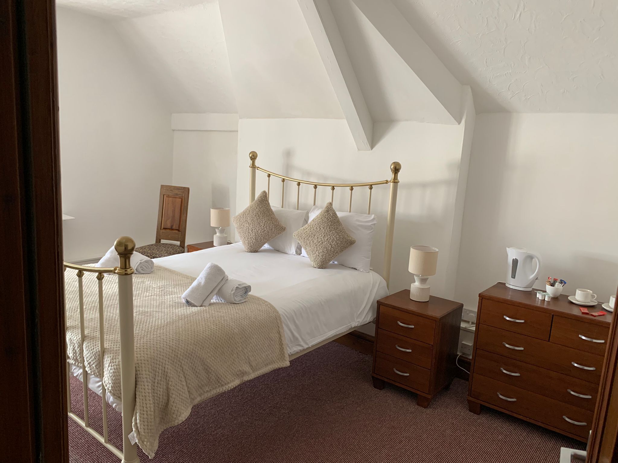 Une chambre bien rangée, avec un lit, des tables de chevet, une commode et une chaise.