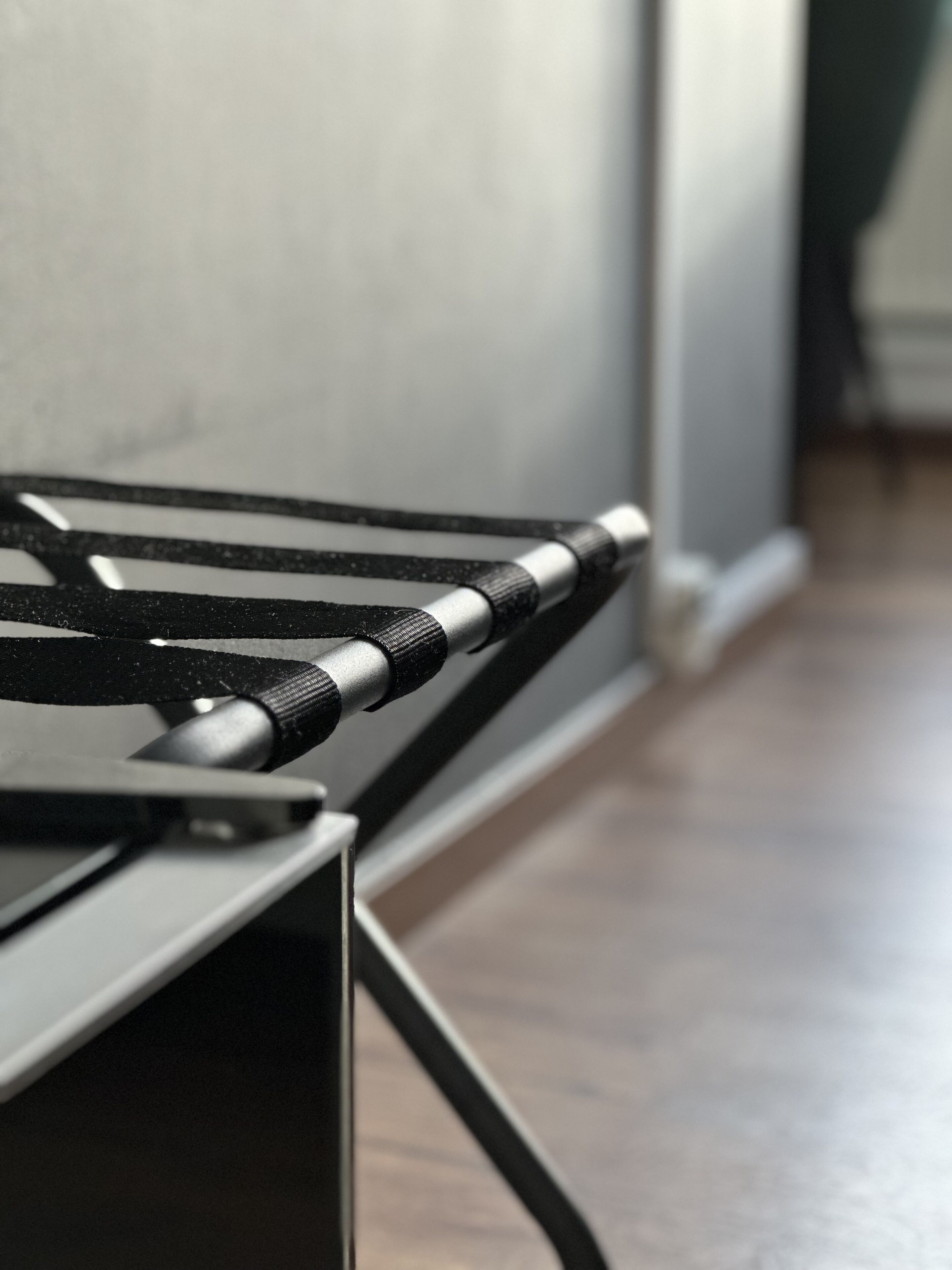 Un primer plano de un objeto metálico con textura vertical y superficie reflectante, posiblemente parte de un mueble o equipo.