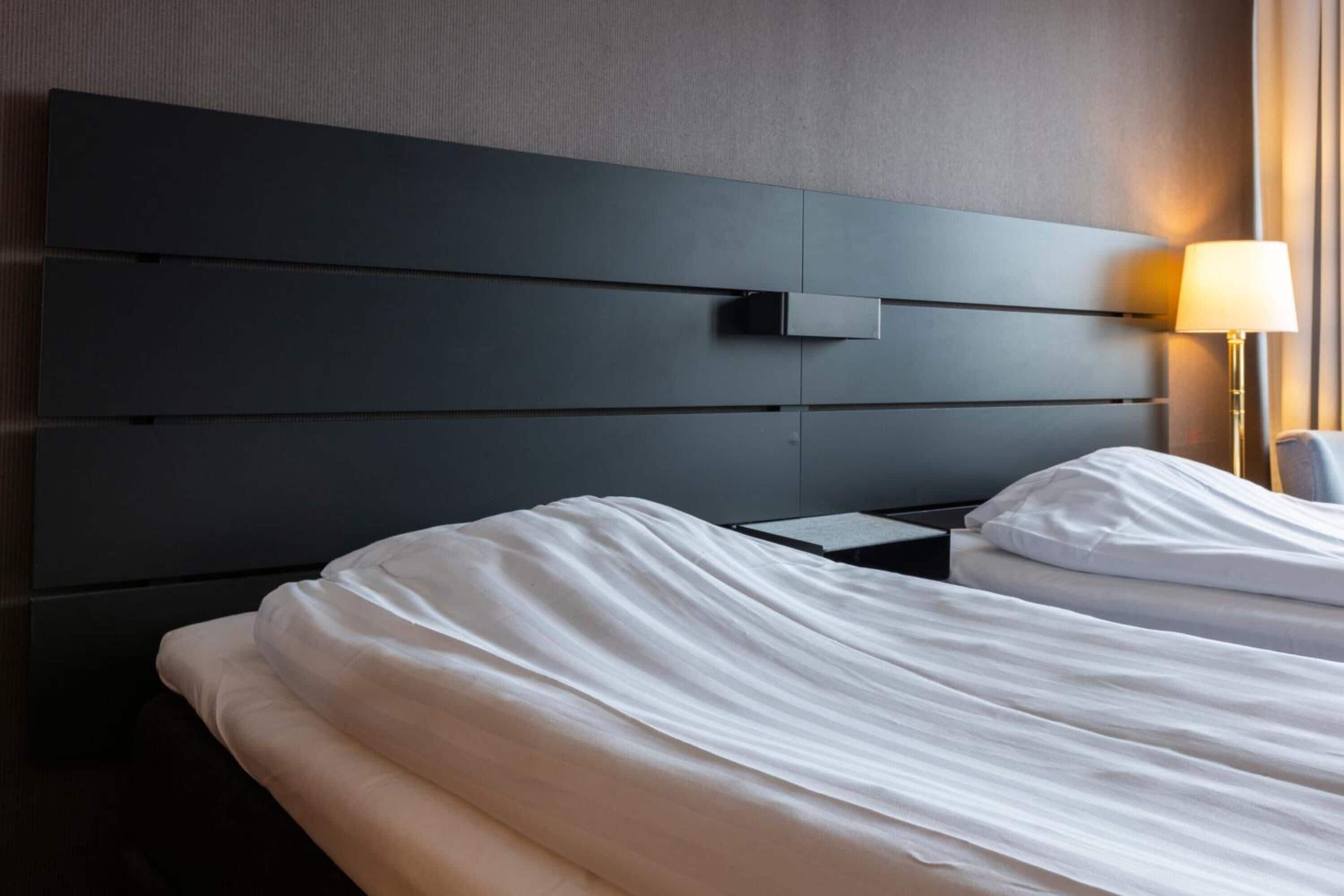 Una habitación de hotel moderna con una cama grande, una mesita de noche y una mesilla.