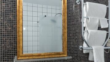 A bathroom with a white sink, a mirror with a gold frame, a towel rack with towels, and a soap dispenser.