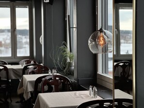 Un restaurante con mesas dispuestas para comer, una planta en maceta y una bombilla encendida en la pared.