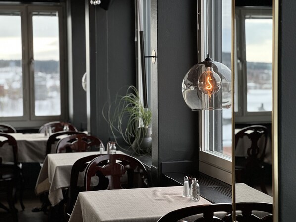 Enjoy a sophisticated dining experience with tables set amidst high ceilings and city views.