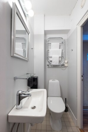Bathroom features a sink, toilet, and mirror, with a shelf and towel rack for convenience.