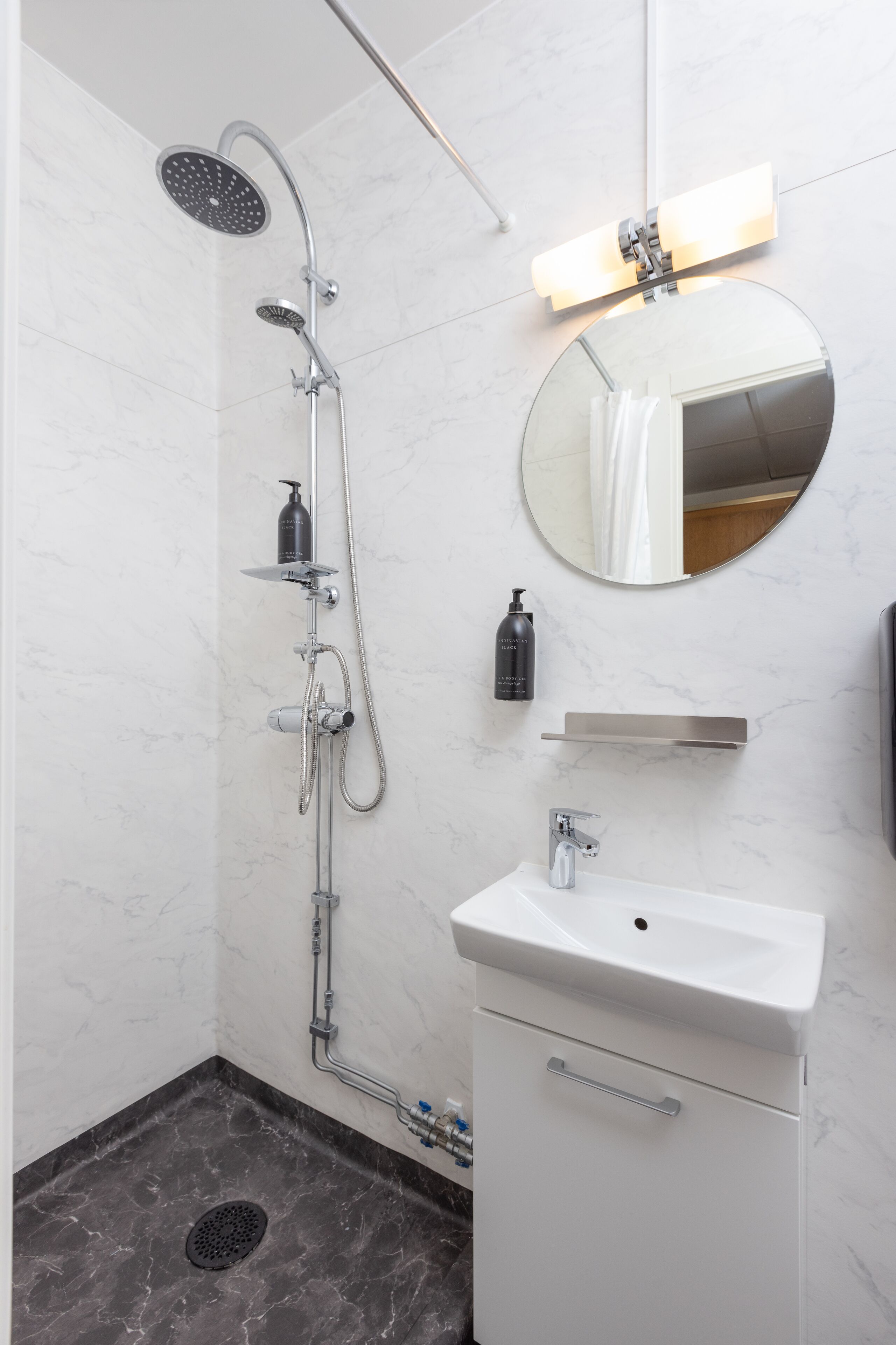 A modern bathroom with a shower, sink, and mirror.