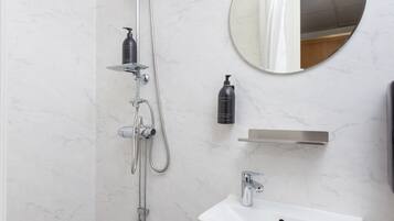 Un baño moderno con ducha, lavamanos y espejo.