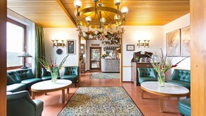 A lobby with green upholstered seating, a marble table, and a chandelier. - Hotel Diana Feldberg (Feldberg)