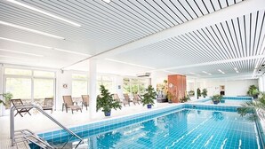 An indoor swimming pool with clear blue tiles, lounge chairs, and potted plants. - Hotel Diana Feldberg (Feldberg)