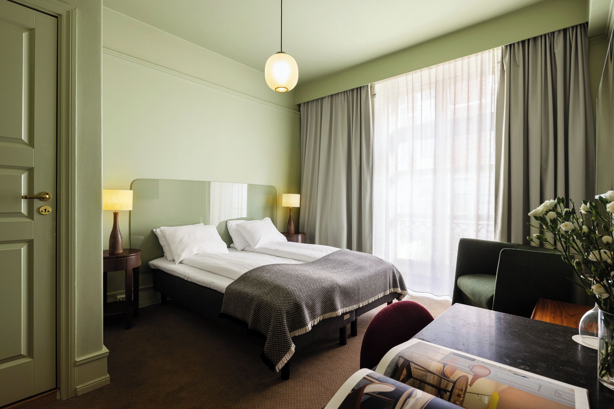 Ein Hotelzimmer mit Bett, Nachttischen, Schreibtisch und Stuhl.
