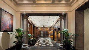 A grand hallway with columns, a chandelier, and potted plants. - Grand Hotel Terminus (Bergen)