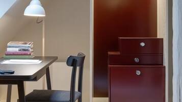 A study with a desk, chair, and books. There is a closet with a hanging rack and a mirror.