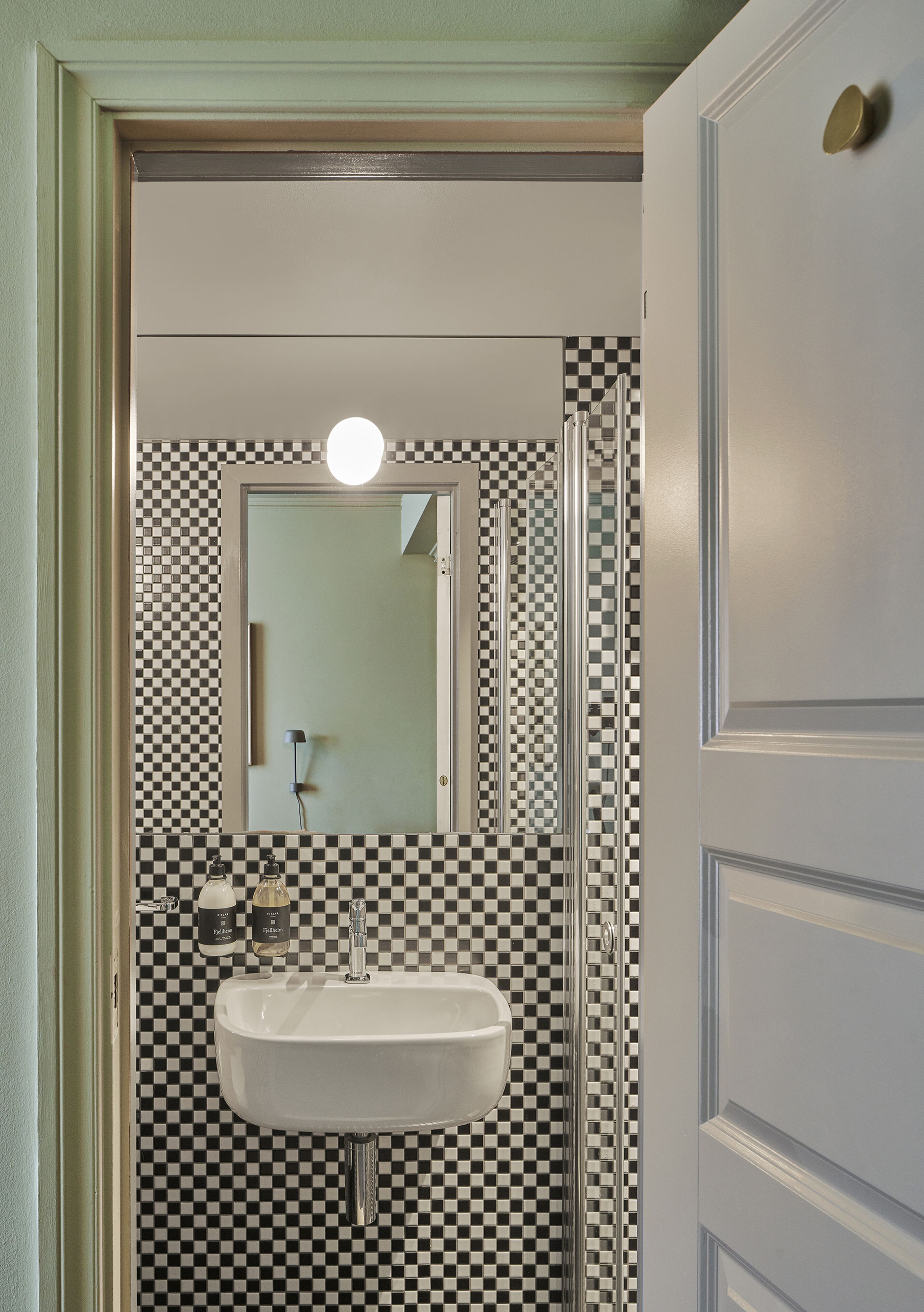 A bathroom with a checkered floor, a sink, and a mirror.