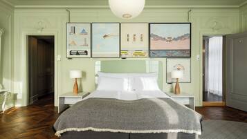 A bedroom with a bed, two bedside tables, a hanging light fixture, and artwork on the wall.