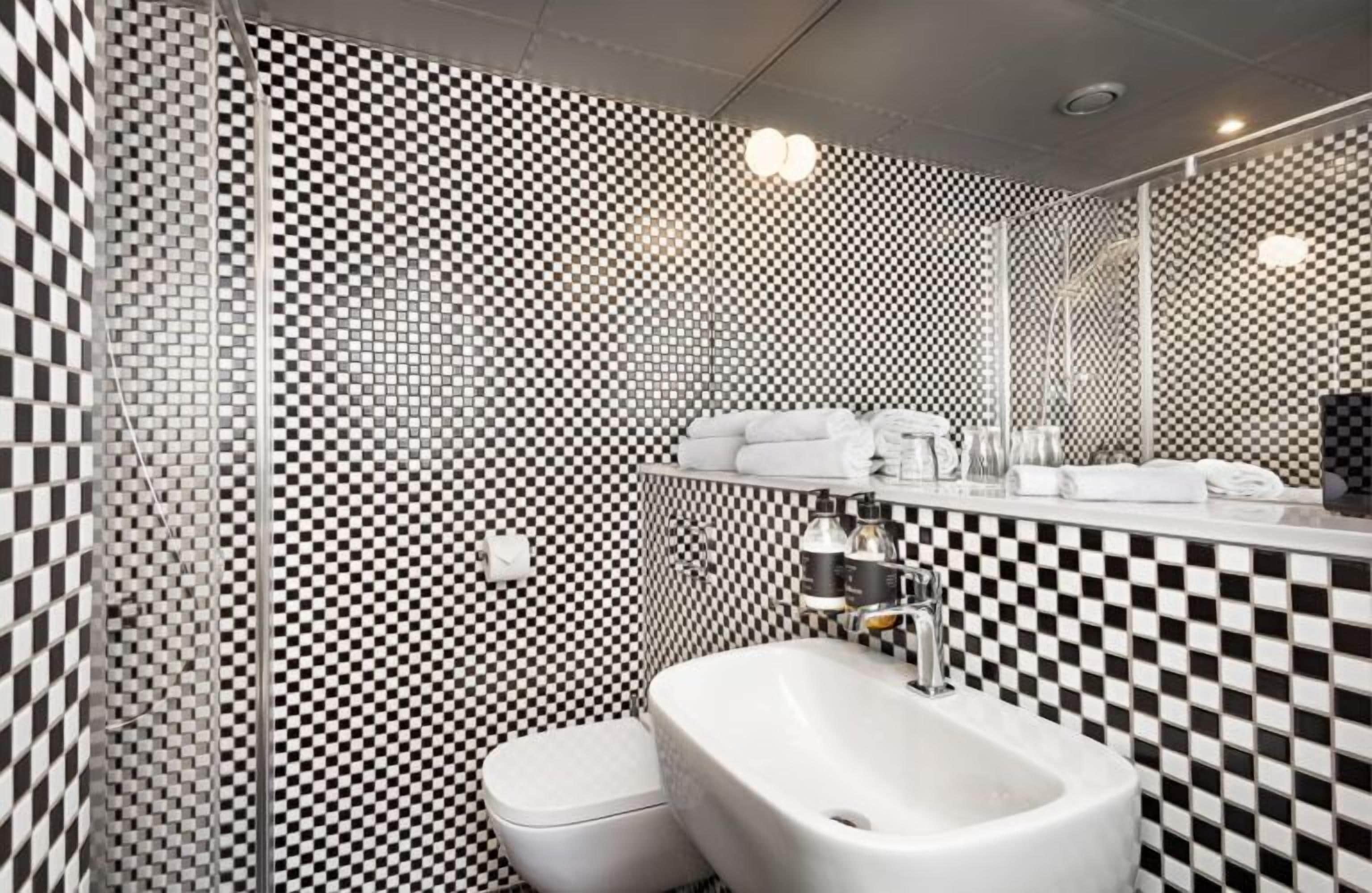 A bathroom with a checkered tile pattern, a white sink, and a toilet.