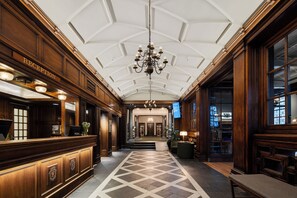 A reception area with a chandelier, a reception desk, and a check-in counter. - Grand Hotel Terminus (Bergen)